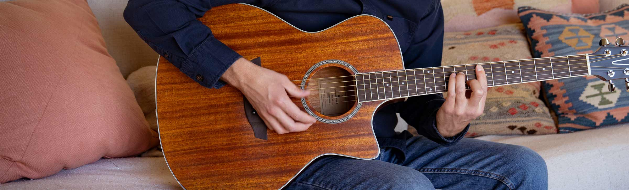 The Manhattan, Rey Spruce, and Victoria guitars resting on a minimalist sofa.