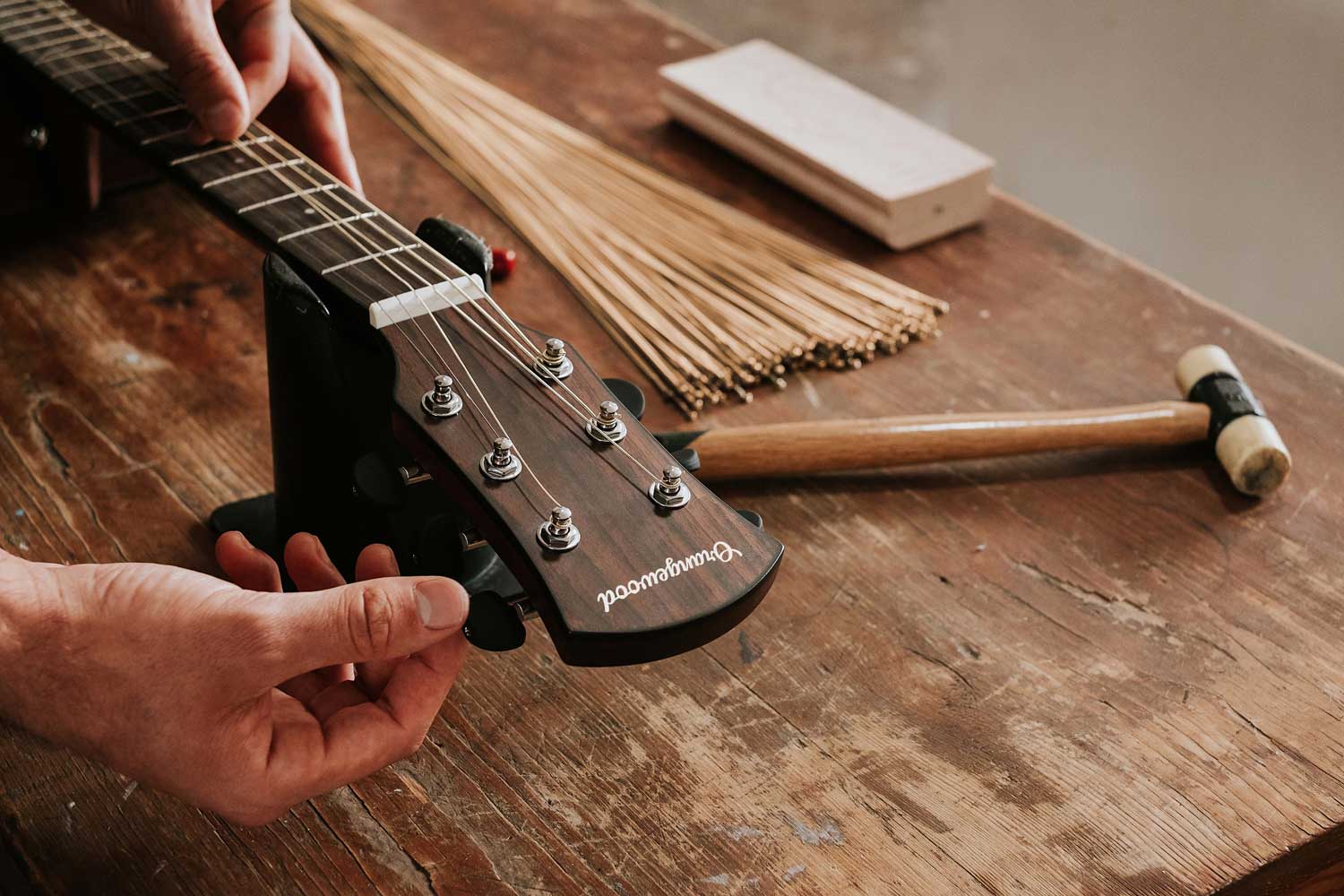 Guitar tech setting up an Orangewood guitar on a workbench
